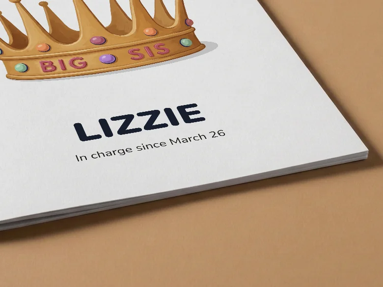 Close-up of a big sister colouring book cover with a crown and the name Lizzie, on tan card, showing the cover card and its thin page edge.