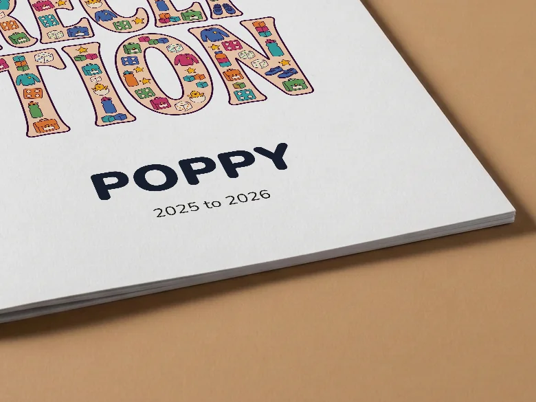 Close-up of a school colouring book cover with Reception lettering and the name Poppy, on tan card, showing the cover card and its thin page edge.